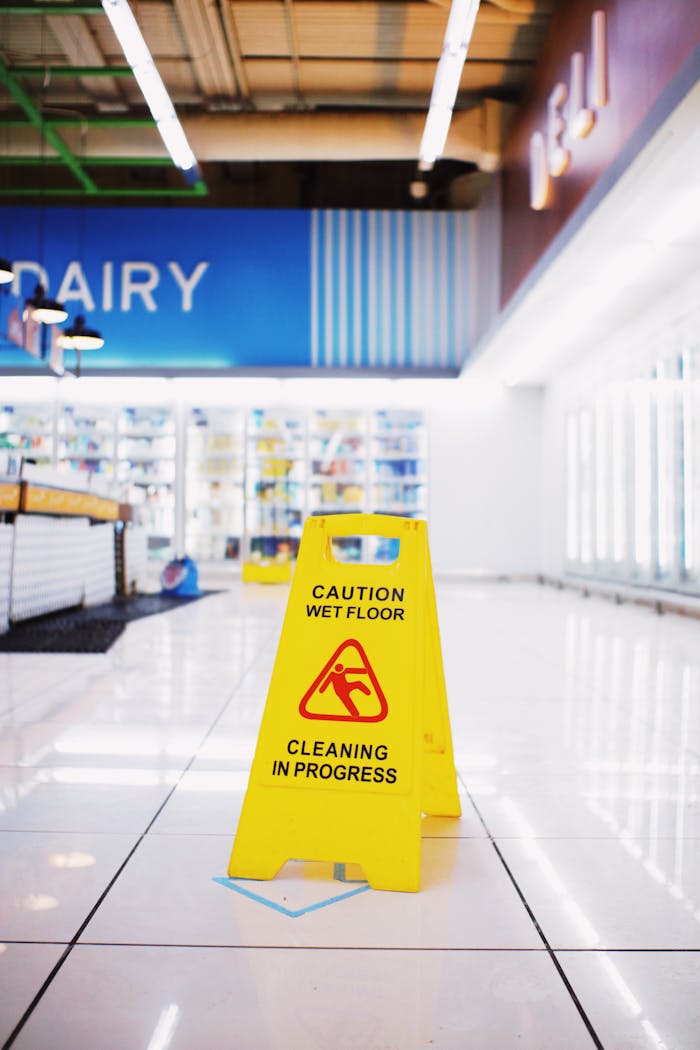 services-01 Yellow plastic warning sing with inscription Wet floor placed in empty store in modern mall