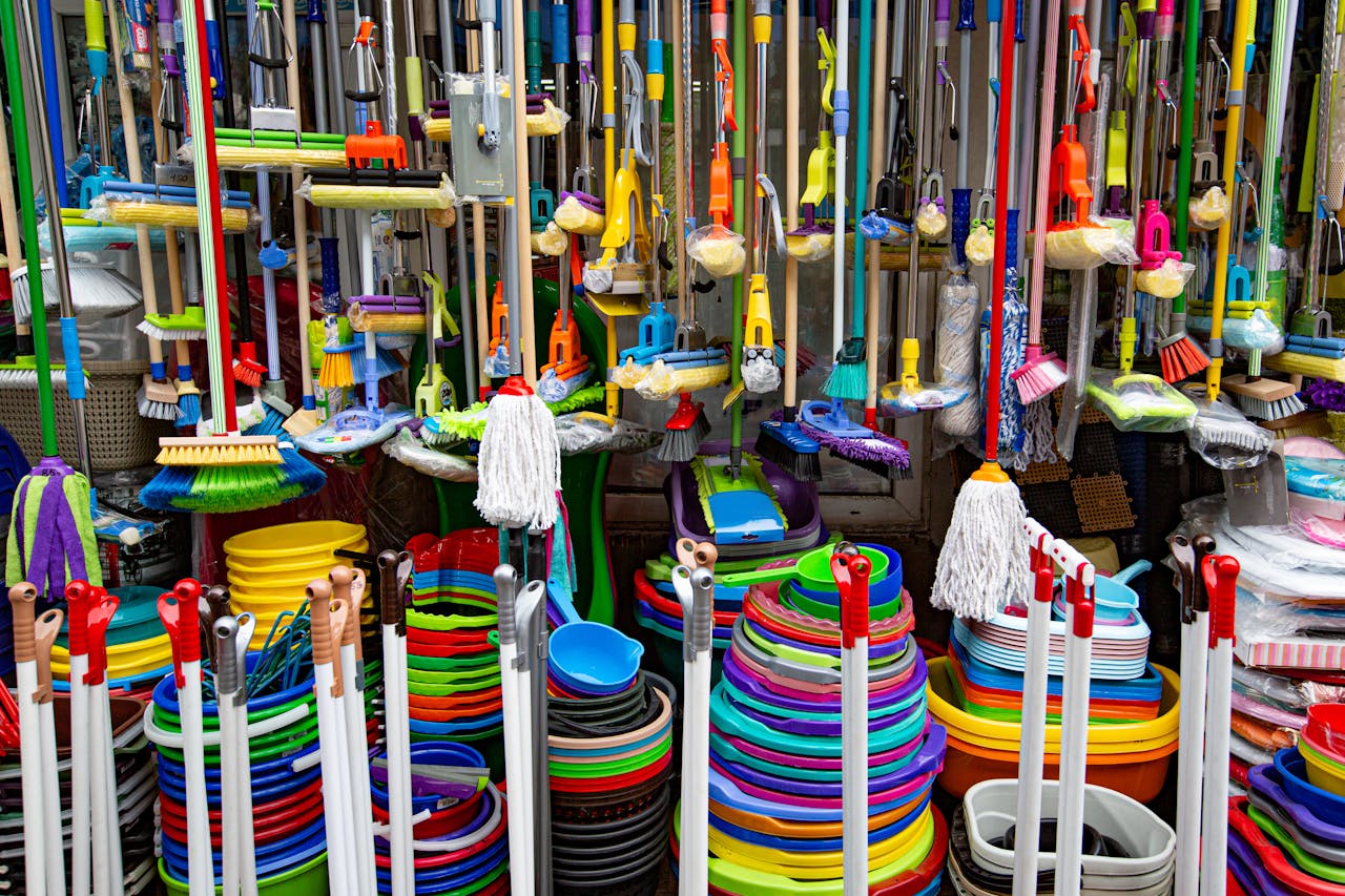 hero-img-01 Various colorful mops and brushes arranged with stack of plastic basins and bins in household goods supermarket